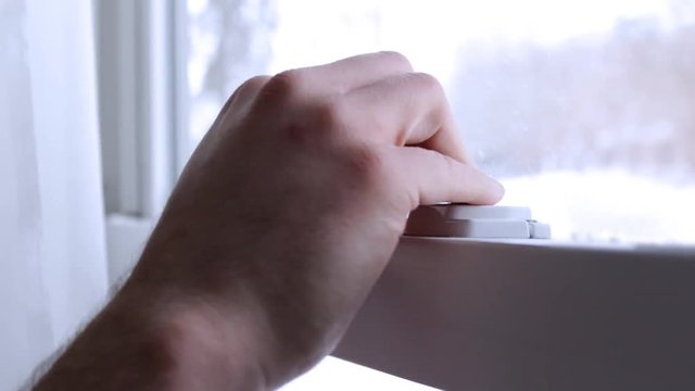Hand locks window latches in ambient white room