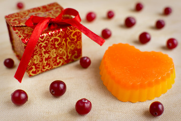 Naklejka na ściany i meble Bright colored exclusive handmade soaps in the shspe of heart. Cranberries and red gift box on the background.