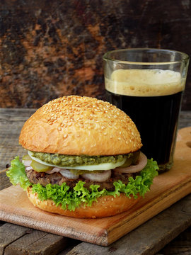veggie burgers with a chop of black beans, lettuce, pickled onions, cucumber and a glass of dark beer on a wooden background. Space for text