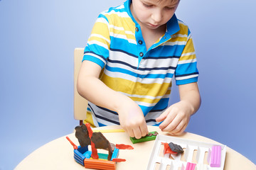 Kid is sculpting a ship with colorful modelling clay.