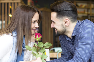 Young couple at cafe with red rose