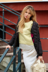 Street style - cute girl in lace skirt, sweatshirt, black down jacket and rough heavy boots on stairs