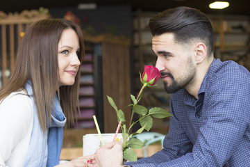 Young couple at cafe with red rose