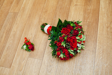 Wedding bouquet and boutonniere on wooden background.
