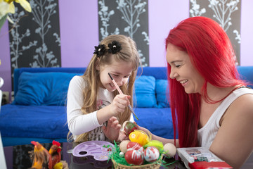 Mom and daughter together painting Easter eggs.