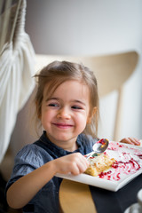 the little girl in cafe eats a dessert