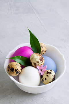 White plate with colourful easter eggs on grey concrete background.
