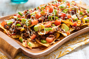 Nacho corn tortilla chips with cheese, meat, guacamole and red hot spicy salsa