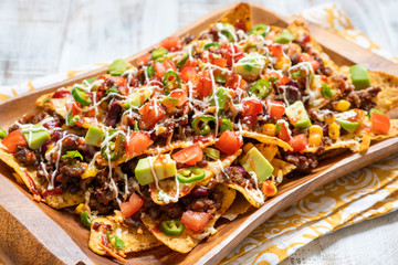 Nacho corn tortilla chips with cheese, meat, guacamole and red hot spicy salsa