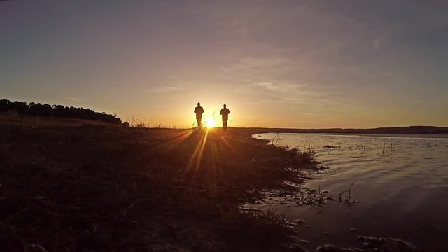 Two men running at sunset along the river bank beautiful the sport