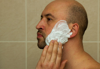 Portrait of a good looking young man putting shaving cream on his face and ready to shave his beard...