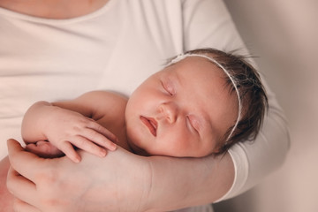 A newborn infant sleeping in the parent's hands.