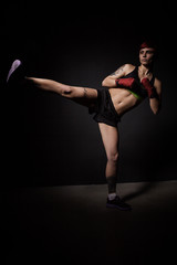 Young tattooed woman kicking with the leg