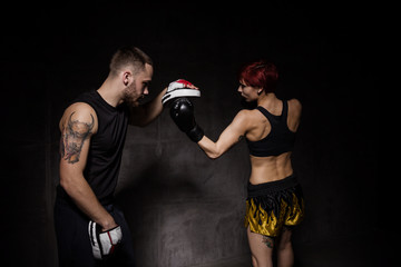 Woman boxer hitting training mitts held a boxing trainer