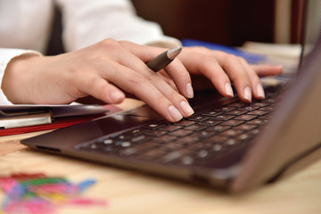 hand with pen typing on laptop