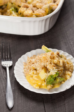 Chicken Divan casserole with broccoli and rice on small white plate with dark wooden background slightly angled shot