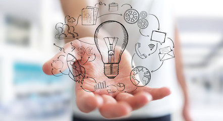 Businessman holding hand drawn lightbulb and multimedia icons
