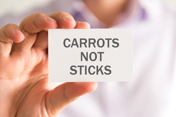 Businessman holding a card with CARROTS NOT STICKS message