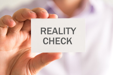 Businessman holding a card with REALITY CHECK message - 140264212