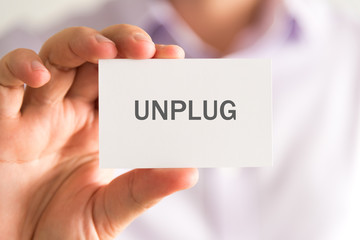 Businessman holding a card with UNPLUG message