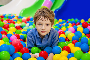 Fototapeta na wymiar Young boy having fun playing with colorful plastic balls.