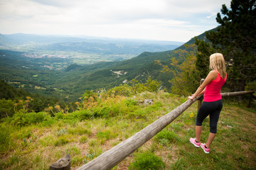 woman rests at fence after workout in nature