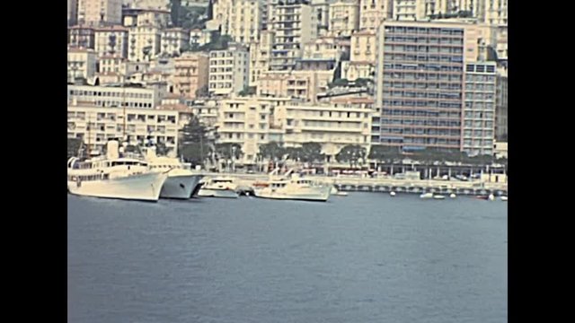 Historic restored footage on 1960s of luxury boats and yachts. at the historical port Hercule in Monte Carlo, France. In front of the roads of the Grand Prix of Monaco.