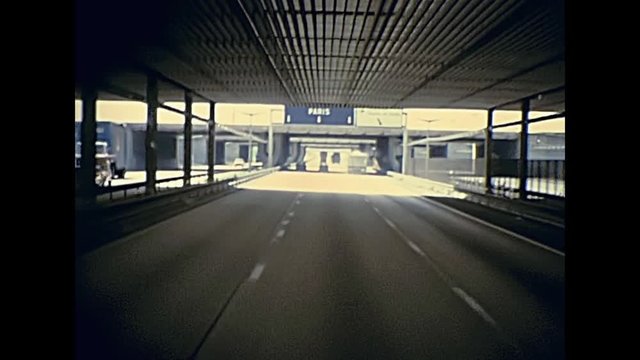 Touristic bus travelling to Paris on the highway under the tunnel bridge in France. Historic restored footage on 1976 in France.