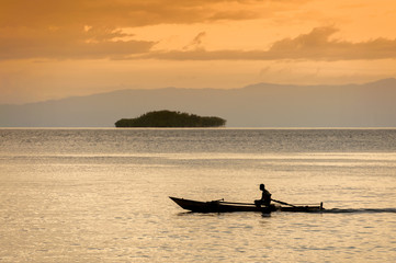 Fototapeta premium Raja Ampat, Indonesia. A lone fishermen heads out for an evening of fishing in the West Papua area near the village of Saporkren.