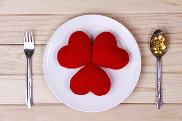 concept red heart on plate with body tonic on spoon and fork on wood background.Health care yourself should be done.