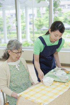 Healthcare worker serving food to senior woman, Kanagawa Prefecture, Honshu, Japan