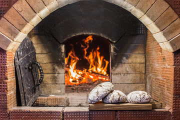Crispy loaf of bread lying on the edge of the Russian stove on the hearth