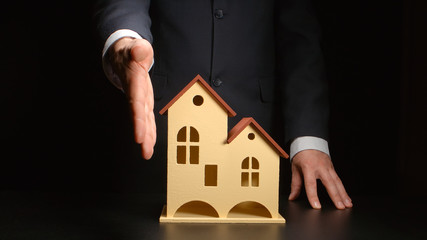 Businessman give handshake over a house model on a table