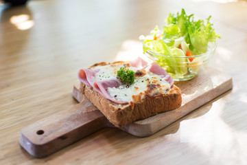 Delicious crusty baguette sandwich with ham cheese and salad on a wooden table