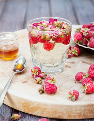 Herbal tea with rose buds and fresh raspberry.