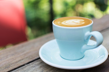 blue cup of hot coffee on natural green background