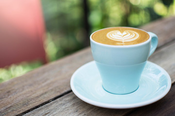 blue cup of hot coffee on natural green background