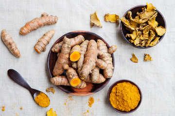 Fresh and dried turmeric roots in a wooden bowl