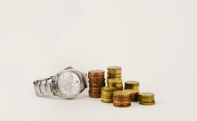 Broken watch with gold coins on white background