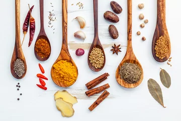 Gordijnen Various of Indian spices and herbs in wooden spoons. Flat lay of spices ingredients chili ,paprika ,peppercorn, dried thyme, cinnamon,star anise and curry powder on the shabby wooden. © kerdkanno