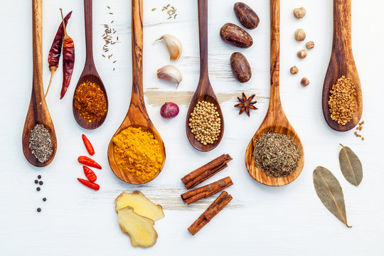 Various of Indian spices and herbs in wooden spoons. Flat lay of spices ingredients chili ,paprika ,peppercorn, dried thyme, cinnamon,star anise and curry powder on the shabby wooden.