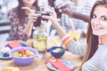 Group of people having dinner together while sitting at wooden table