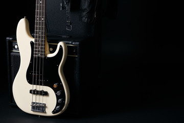 Black and white electric bass guitar with amplifier,hard case and Leather biker jacket on black background with Copy spase.
