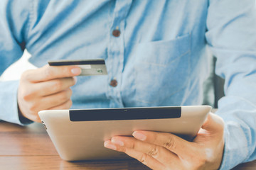 Man holding tablet pc and credit card on table