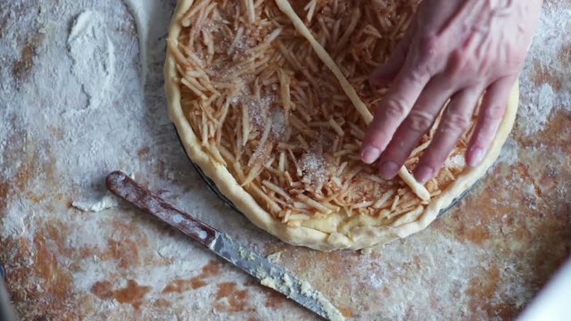 A woman is preparing an apple pie in a home kitchen