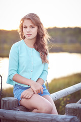 Teenage girl in a blue dress over outdoor natural field.