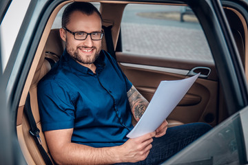 A man sits on a back seat of a car.