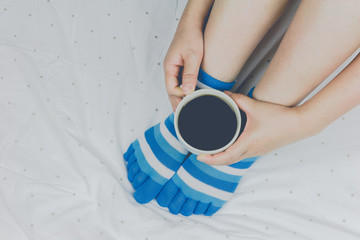 Woman holding cup of coffee on the bed