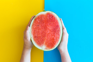 Hand holding watermelon on colourful background