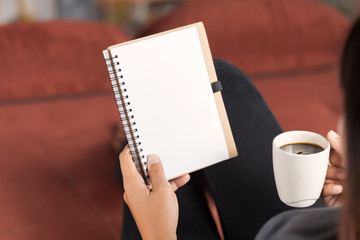 selective focus on woman reading notebook and holding coffee cup in morning